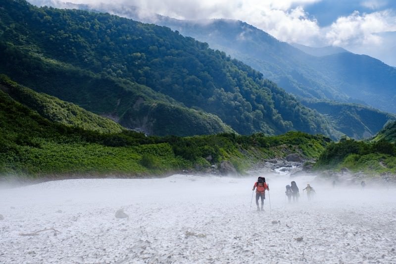 吹き下ろす冷風の白馬大雪渓を登る登山者達（白馬岳）の写真