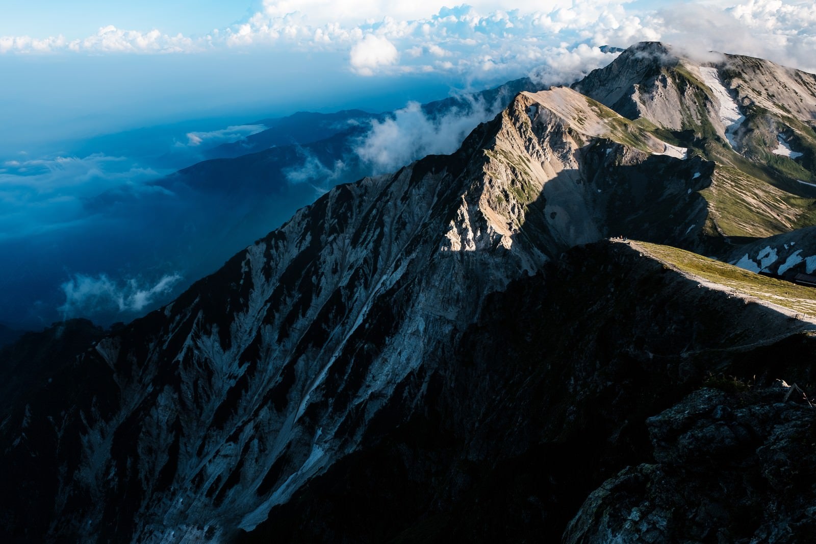 「夕日が当たらない杓子岳の切り立つ山肌」の写真