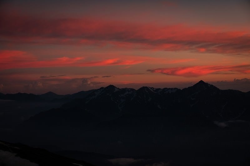 夕焼けと日没を迎える立山連峰の写真