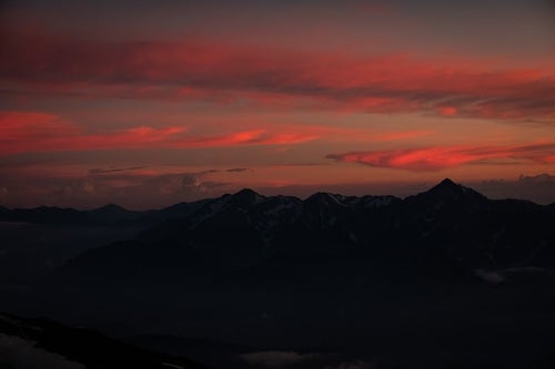 夕焼けと日没を迎える立山連峰の写真