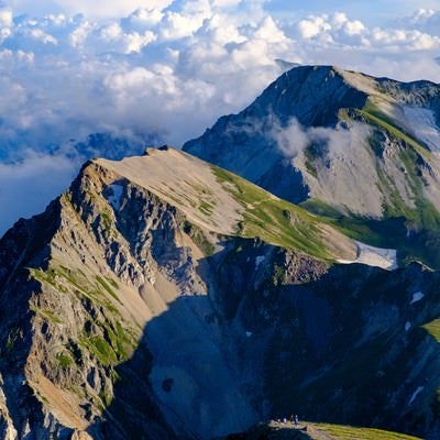 登山道を歩く登山者と杓子岳の写真