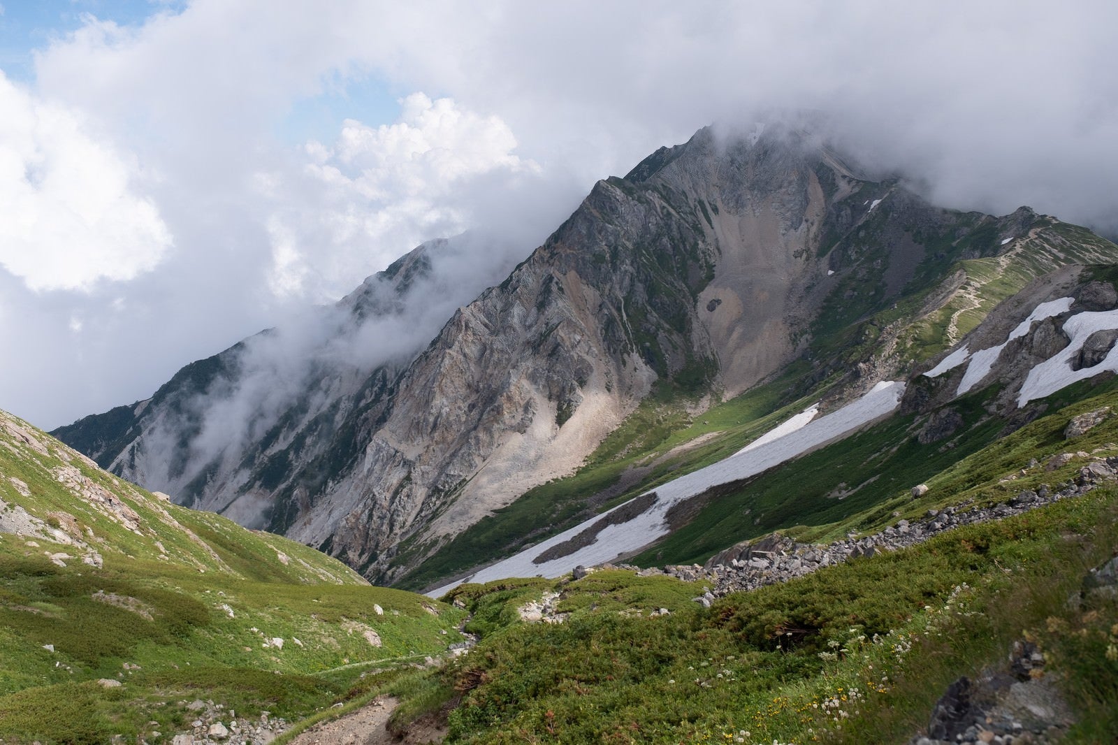 「白馬岳（しろうまだけ）の雪渓と沸き立つ雲間に見える山々（白馬岳）」の写真