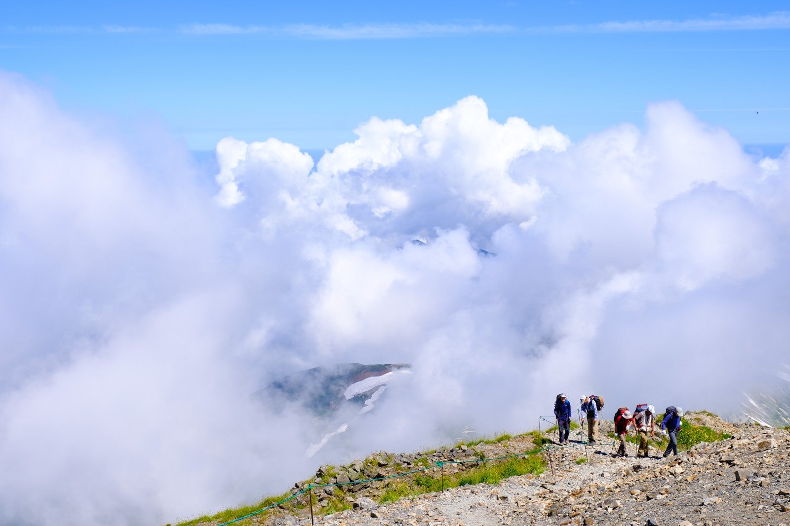 「白馬岳稜線を歩く登山者の後ろに迫る雲」の写真
