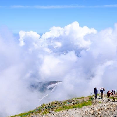 白馬岳稜線を歩く登山者の後ろに迫る雲の写真