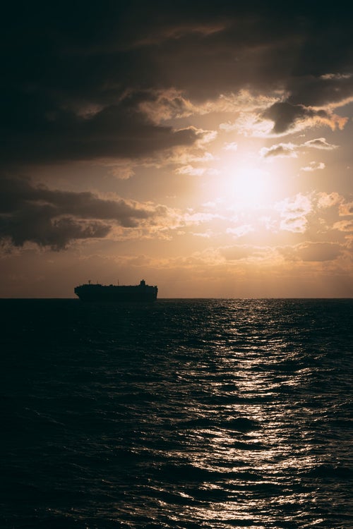 太陽と海上のタンカー船の写真