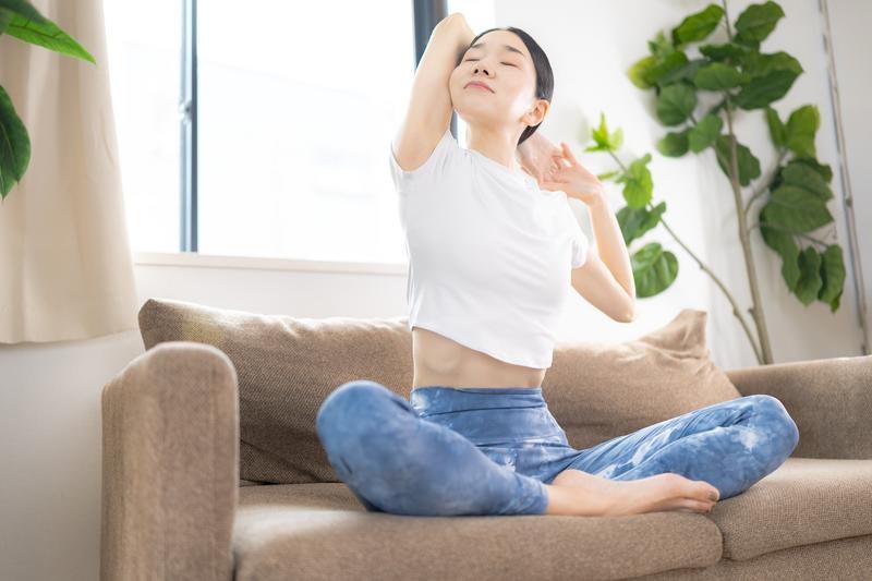 ソファでくつろぎながら上半身を大きく伸ばすストレッチタイムの写真