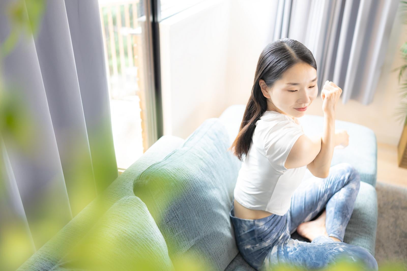 「ソファーの上でストレッチをする女性」の写真［モデル：ひるかわえみこ］