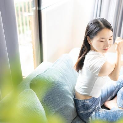 ソファーの上でストレッチをする女性の写真