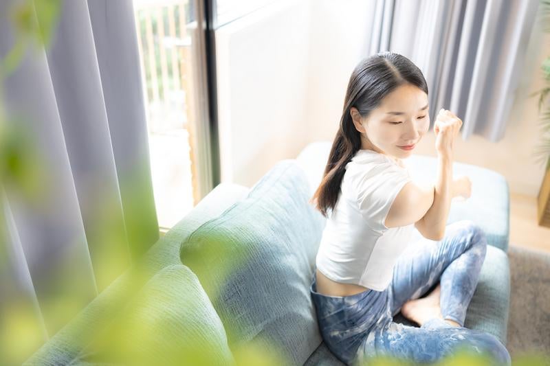 ソファーの上でストレッチをする女性の写真