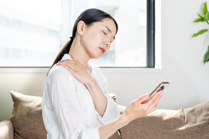 スマホ首・巻き肩に悩む女性の写真