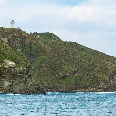与那国島の海岸線に建つ灯台と岩礁の景観の写真