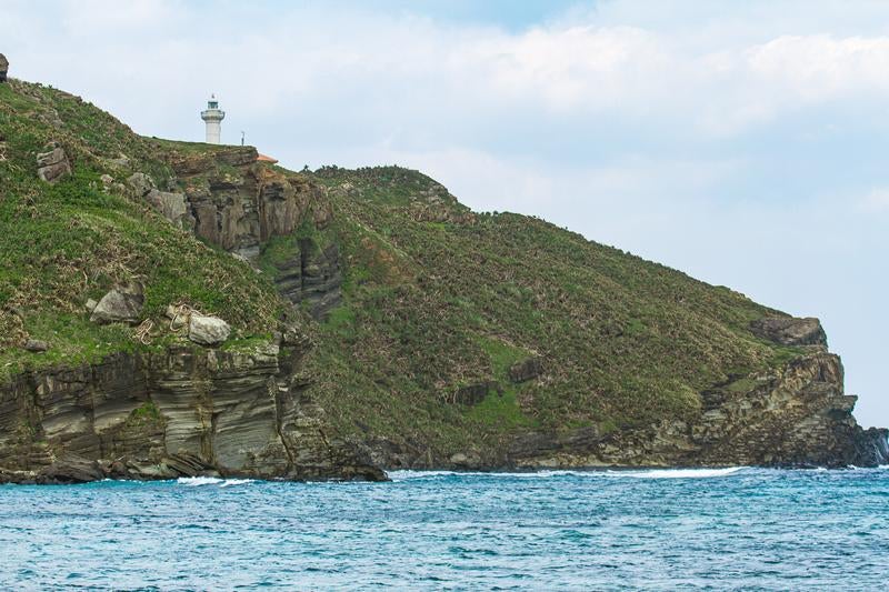 与那国島の海岸線に建つ灯台と岩礁の景観の写真