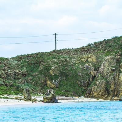 岩場と白砂浜が広がる与那国島の海岸風景と送電線の写真