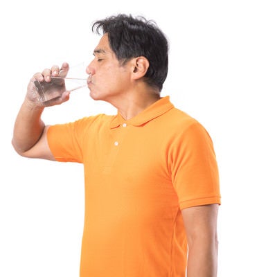 勢いよく水を飲む中年男性の写真
