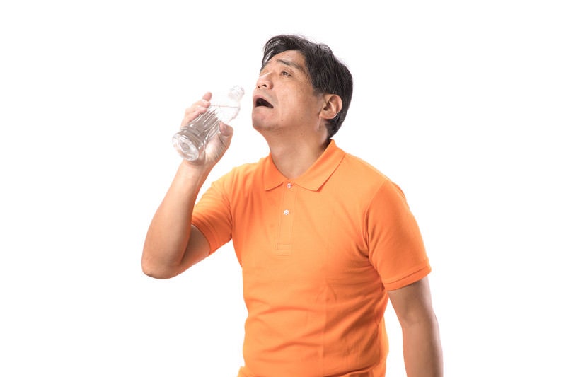 脱水症状で水を欲する中年男性の写真