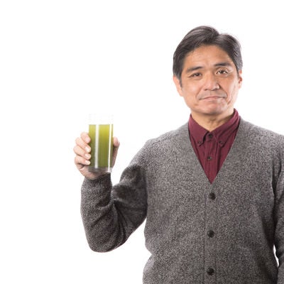 青汁で健康をアピールする中年男性の写真