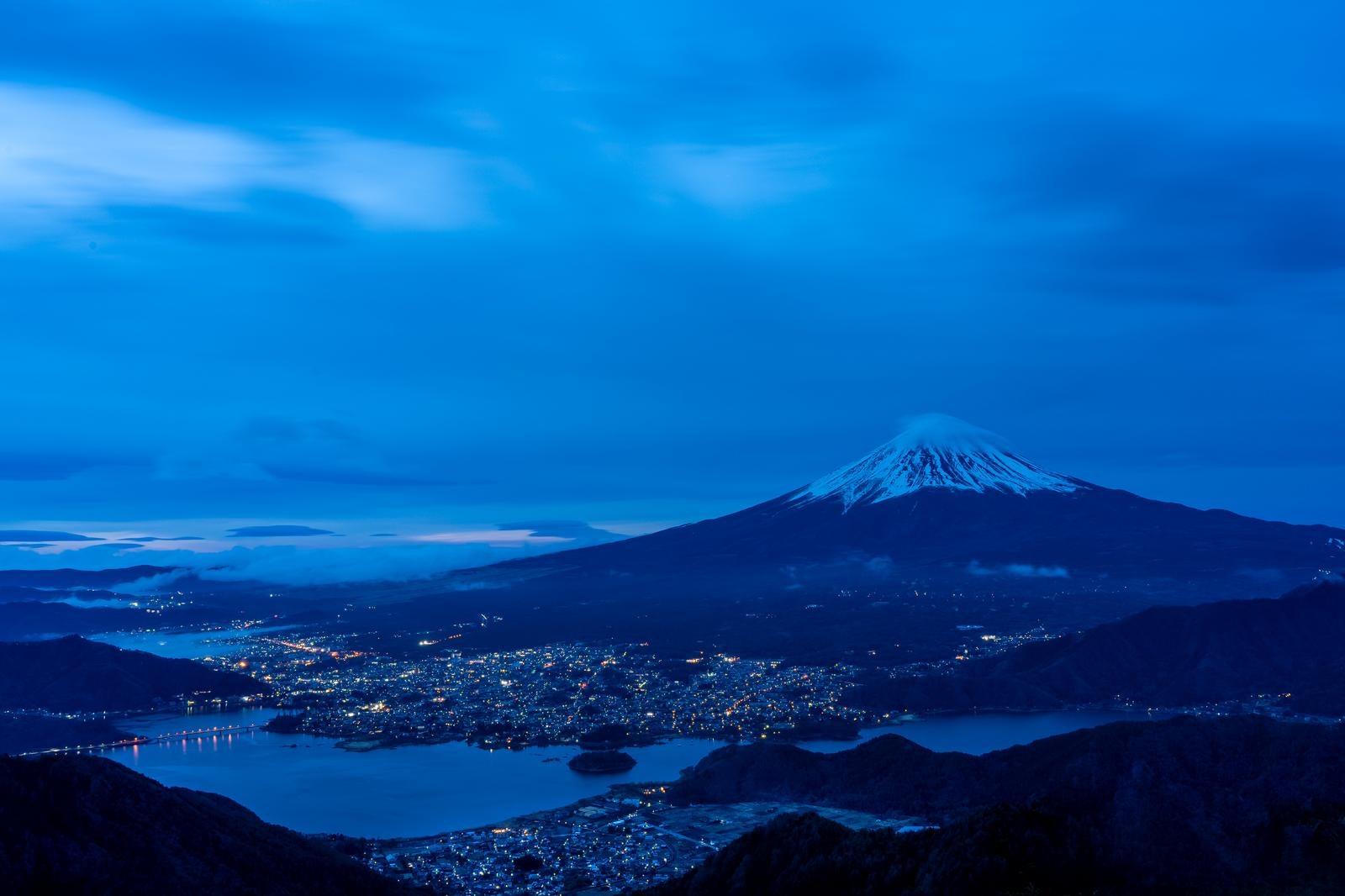 「富士の夜 街明かりと共に輝く山の姿」の写真