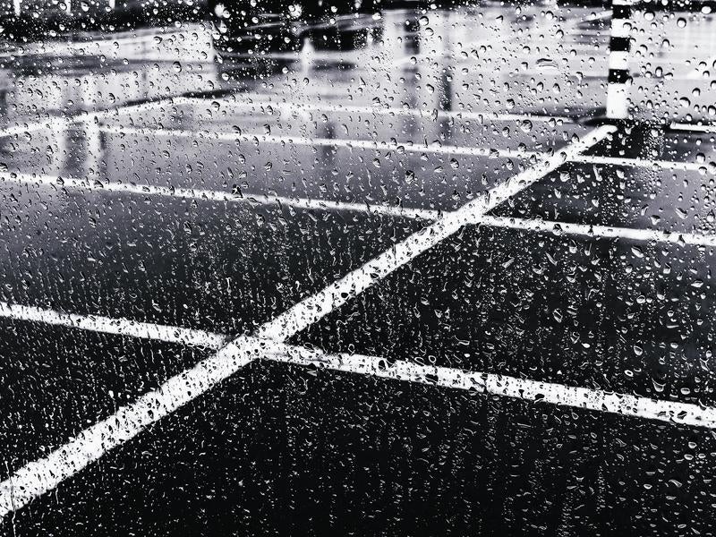 大雨の中で車のガラスに飛び散る水滴の写真