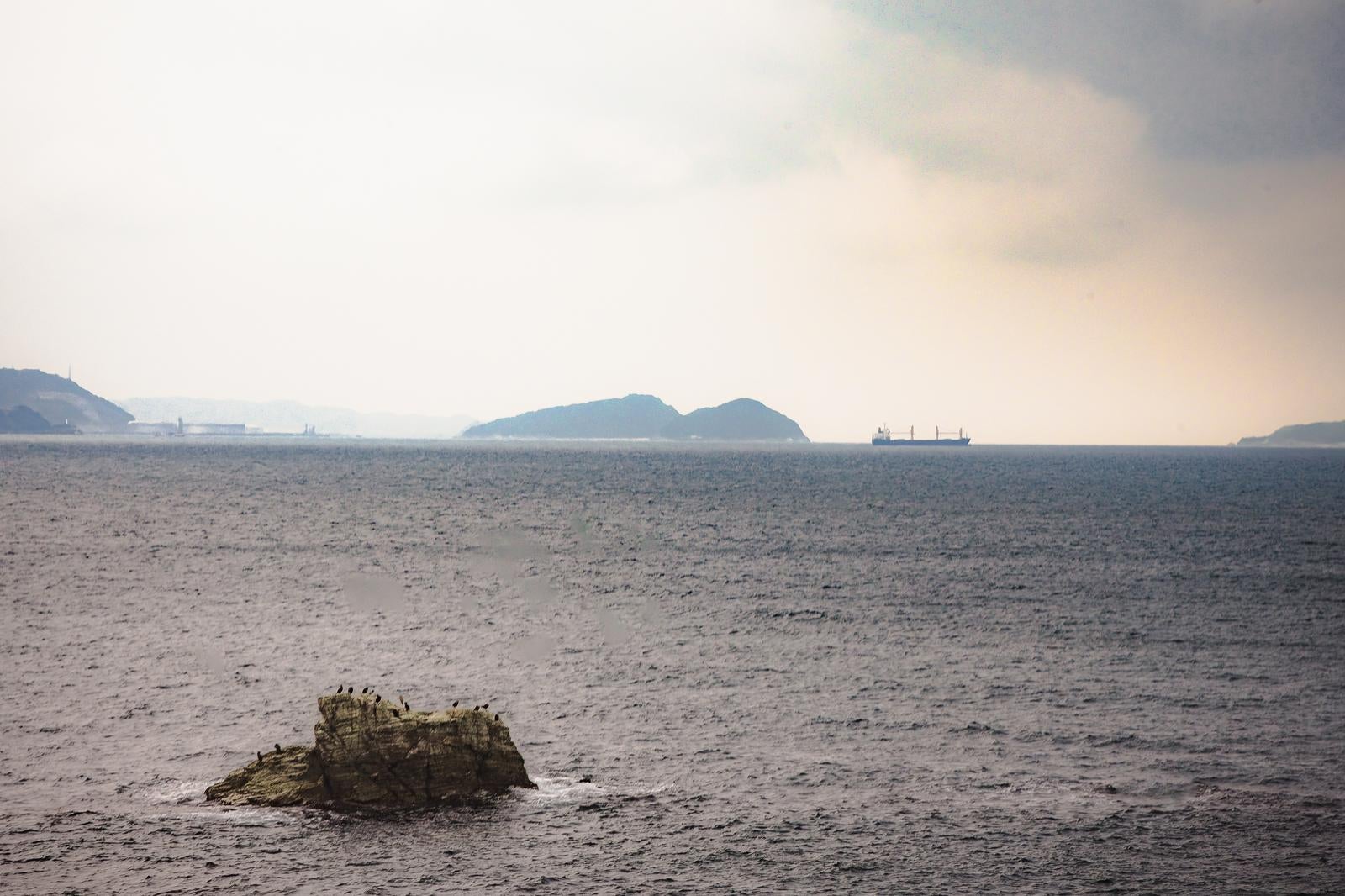 「和歌山県の海沿いから見える船と岩」の写真