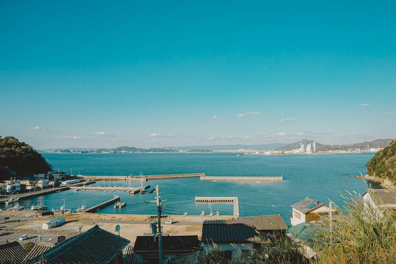 静かな海と遠くに広がる都市の景色（和歌山県塩津漁港）の写真