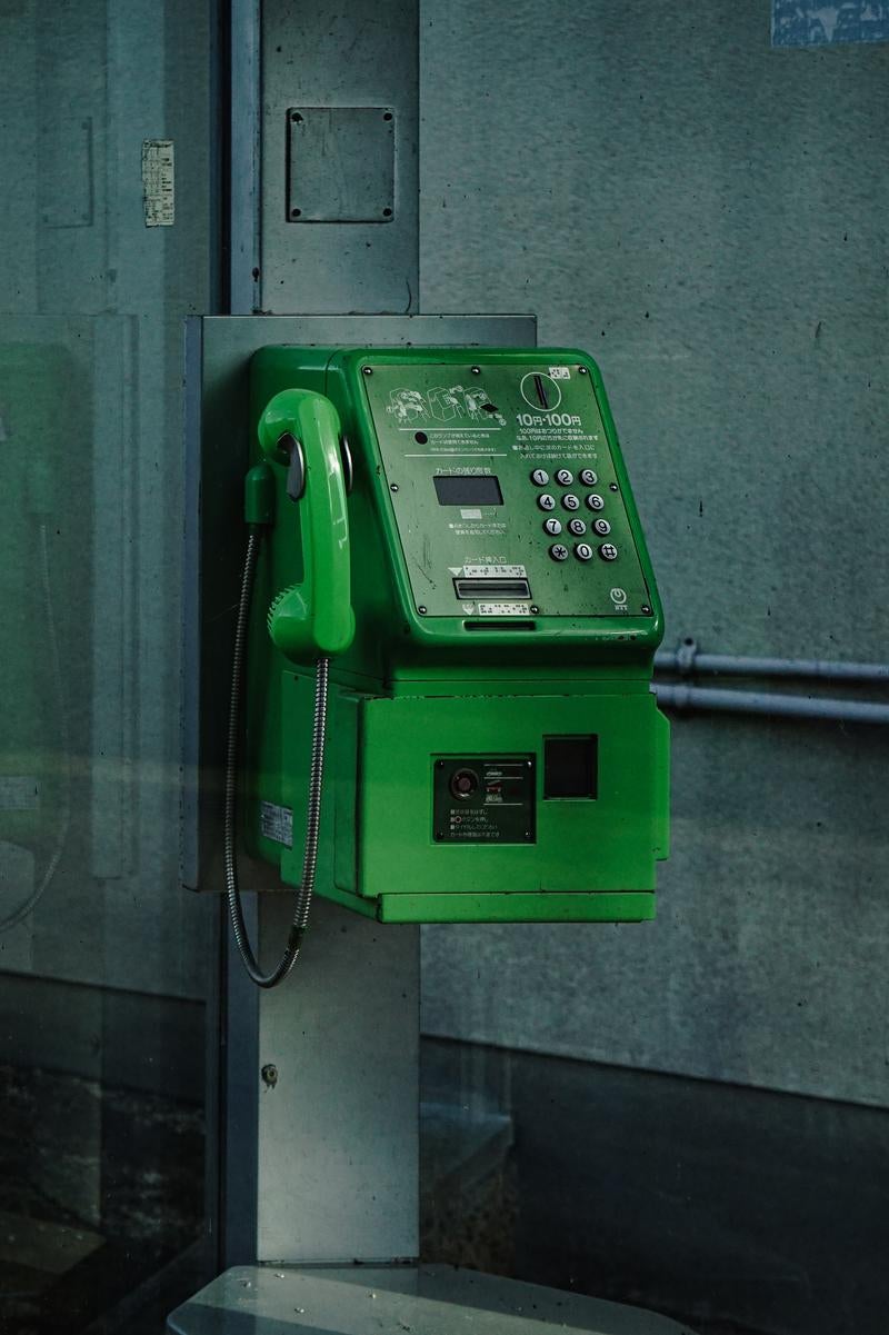 「電話ボックスの内部に設置された公衆電話」の写真