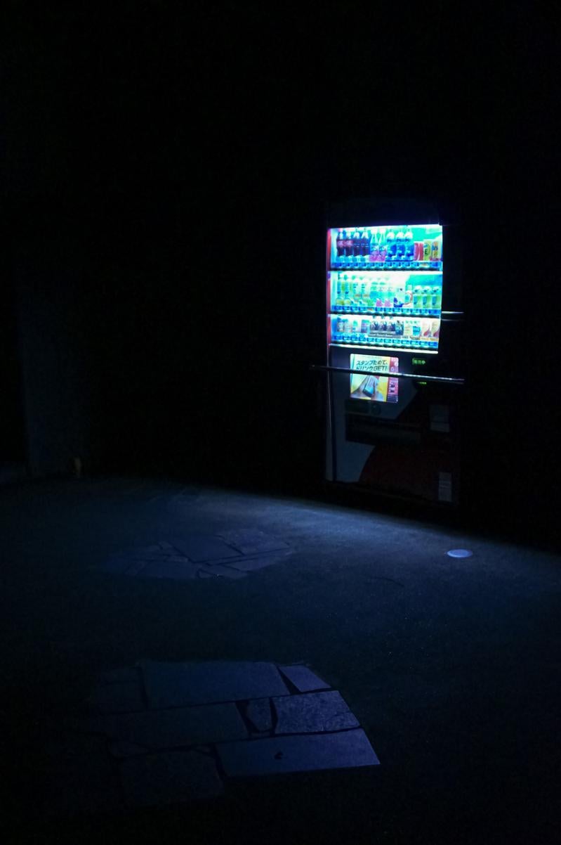暗闇の中で光る自動販売機の写真