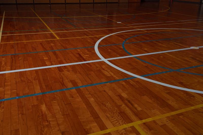 体育館のバスケットボールコートのラインと木製フロアの写真