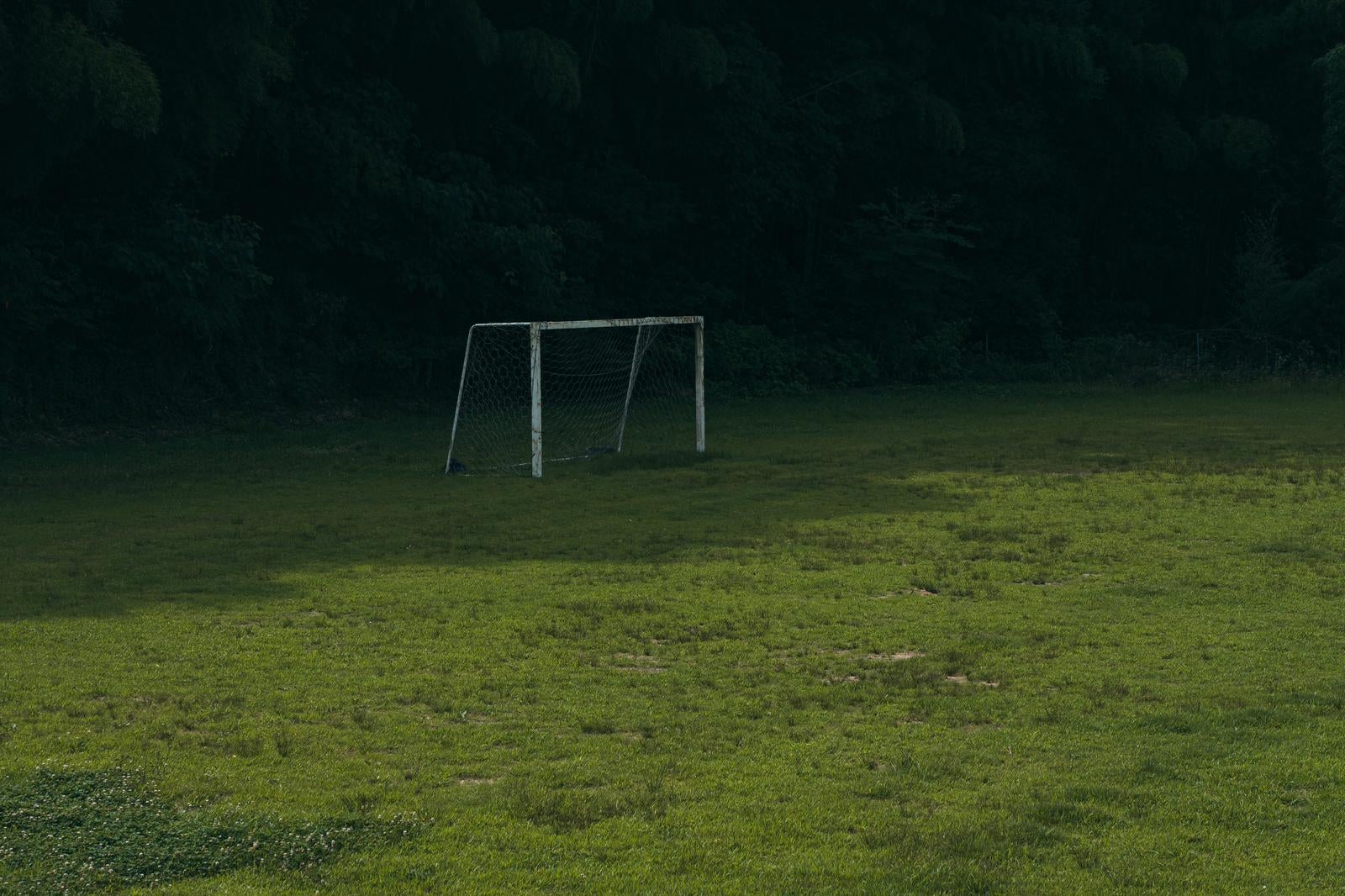 「芝グラウンドの日陰のサッカーゴール」の写真