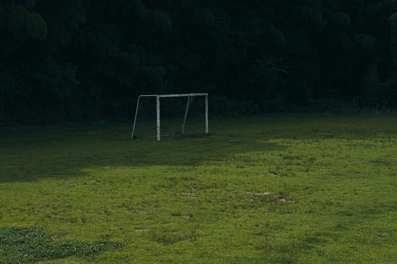芝グラウンドの日陰のサッカーゴールの写真