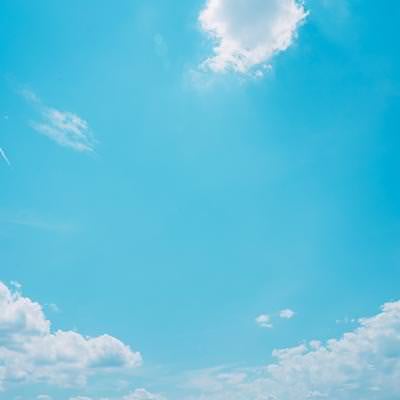 青空に浮かぶ白い雲と飛行機雲の写真