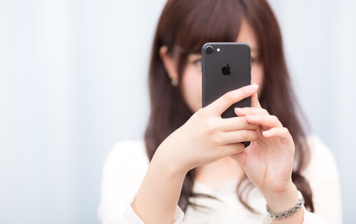 マットブラックカラーのスマートフォンを操作する女性の写真