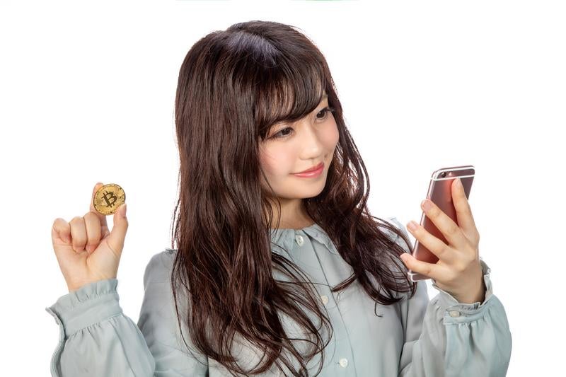 スマホでビットコインのトレードをする女性の写真