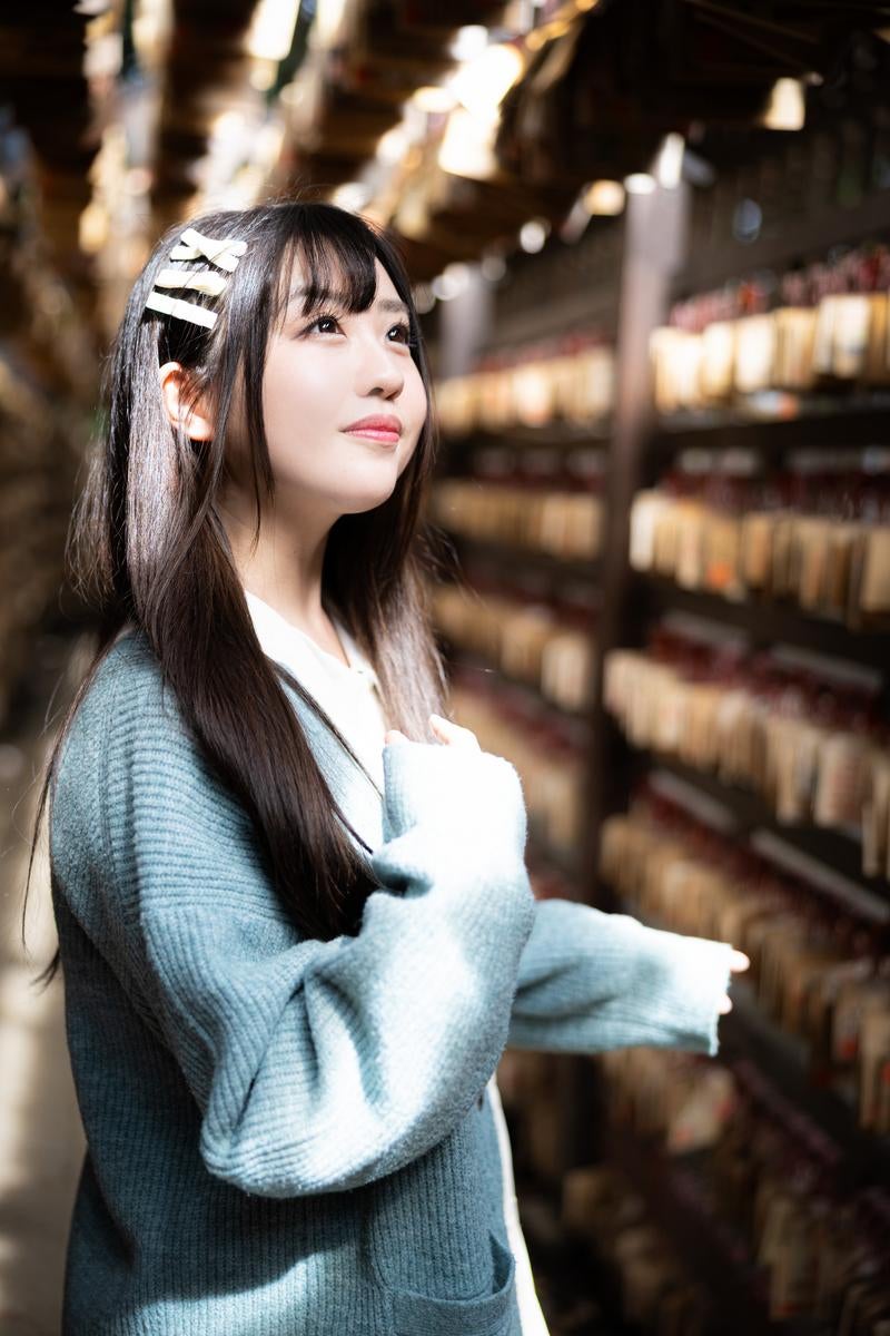 絵馬の前で願い事をする彼女の写真