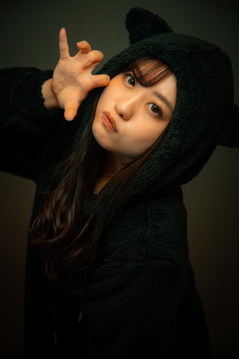 猫耳フードをかぶってポーズを取る女性の写真