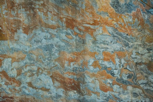 茶色のシミとヒビが広がる石材の写真