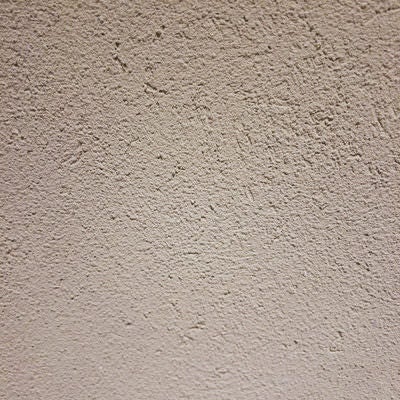 シミが浮かぶ白いモルタルの壁(テクスチャー)の写真