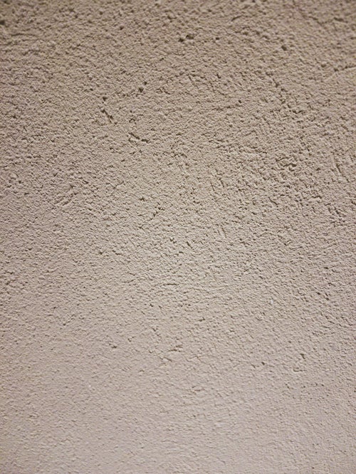 シミが浮かぶ白いモルタルの壁(テクスチャー)の写真