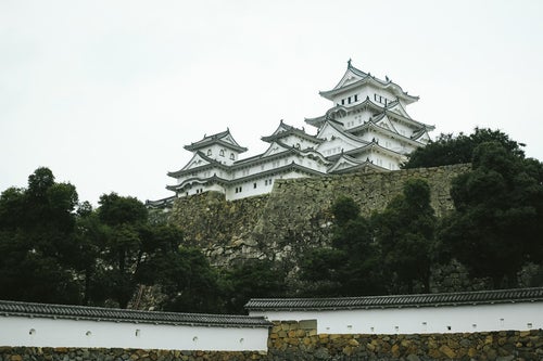 石垣の上にそびえる日本の城（姫路城）の写真