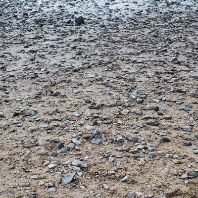 角のある小石が埋まる地面のテクスチャーの写真