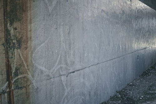 うっすらと落書き後の残る殺風景な壁の写真