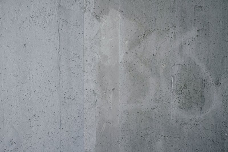 小さな穴が開いた落書き跡の残るコンクリート壁（テクスチャー）の写真