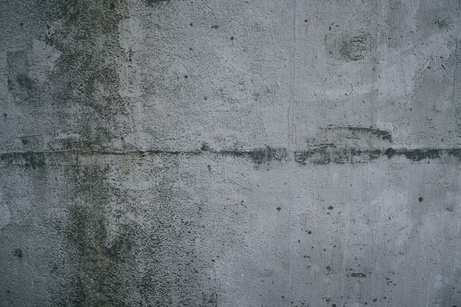 「汚れに薄っすらと落書き跡が浮いたコンクリート壁（テクスチャー）」の写真