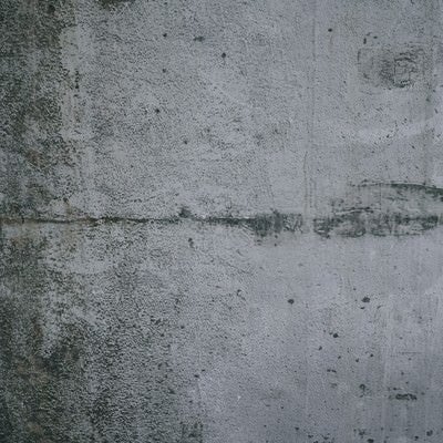 汚れに薄っすらと落書き跡が浮いたコンクリート壁（テクスチャー）の写真