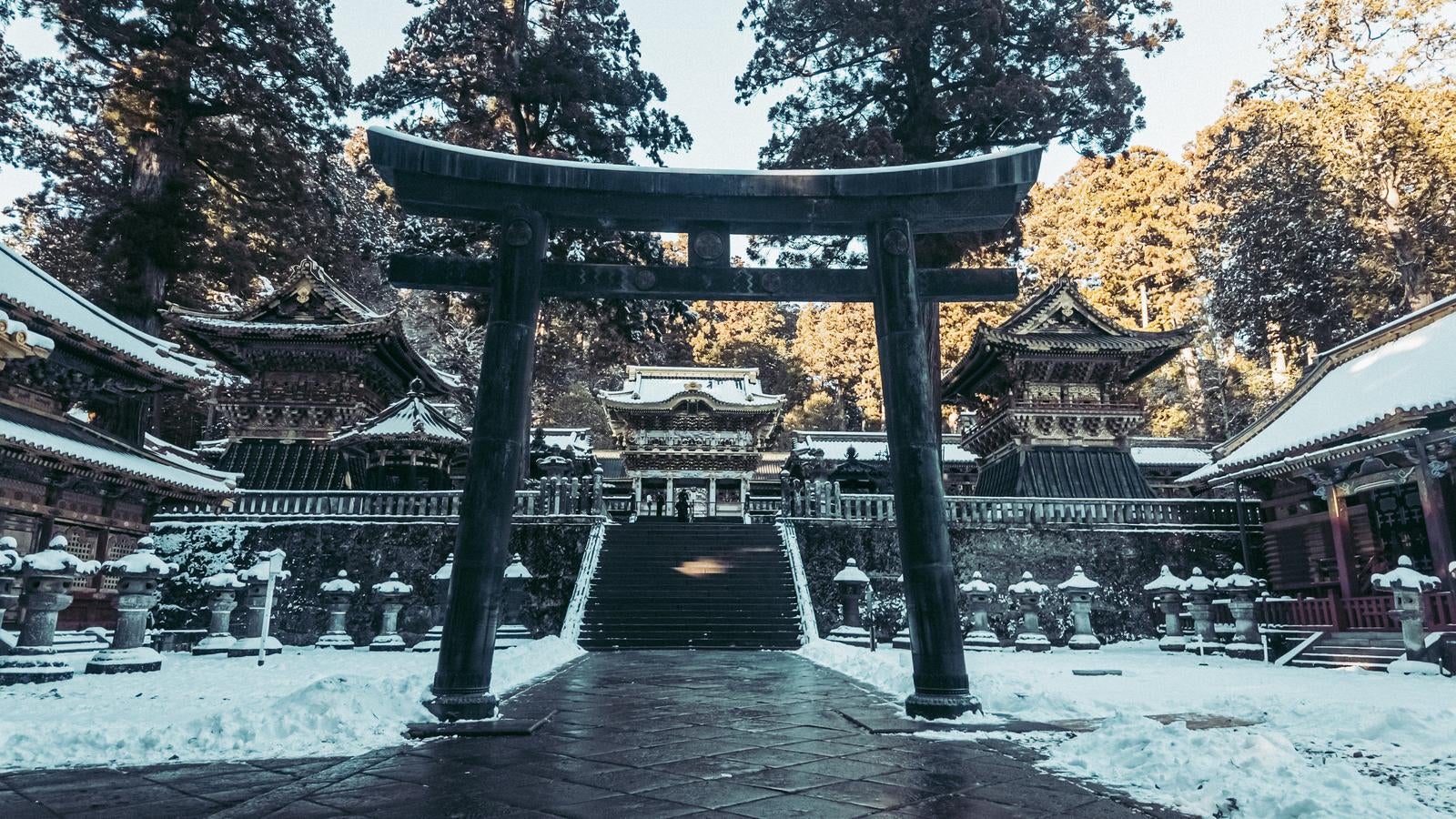 雪の日光東照宮、大きな黒い鳥居と奥の雪化粧した本殿群