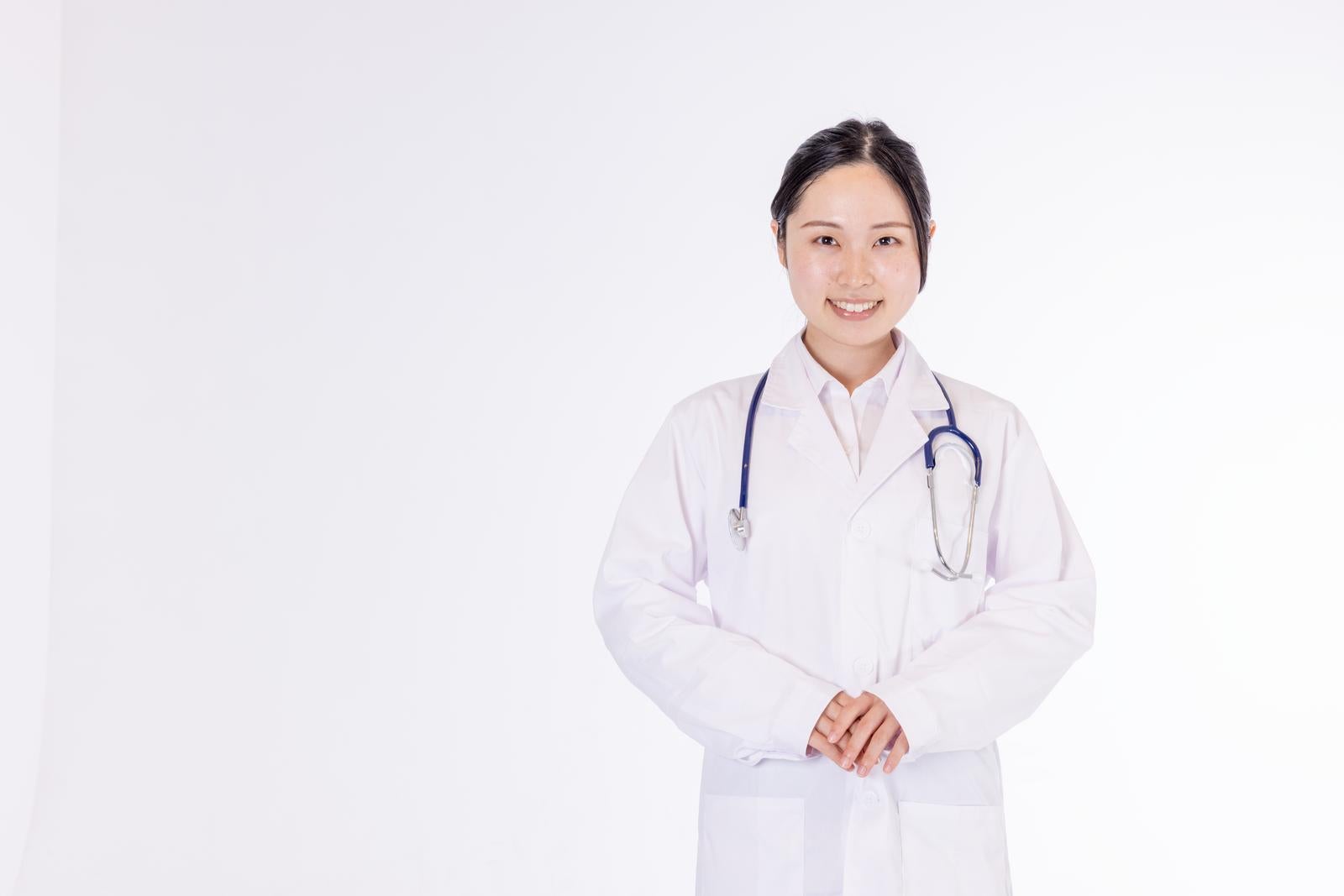白衣を着た女性医師が聴診器を首にかけて立つポートレート［モデル：吉屋ゆり］