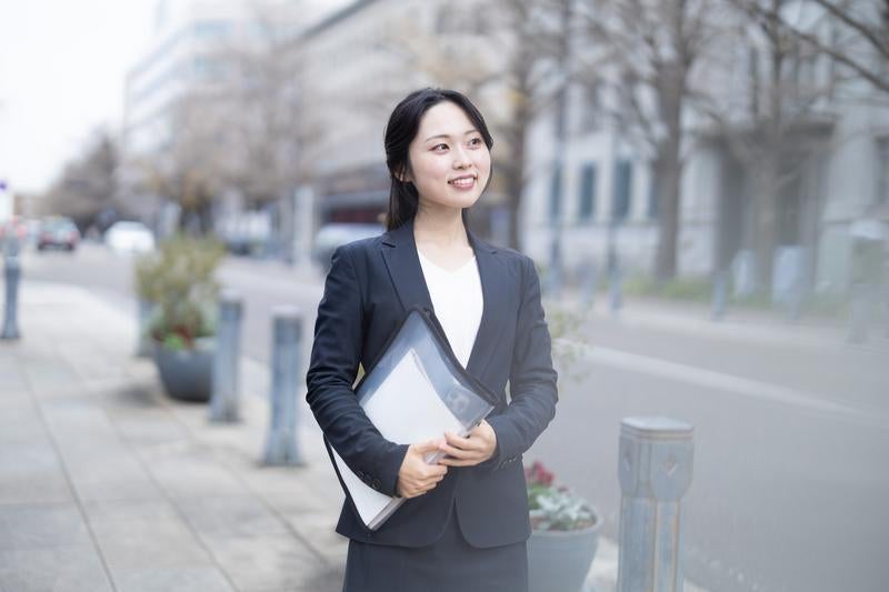 書類を抱えて外回りに向かうスーツ姿のOL