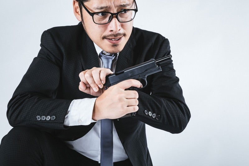 拳銃をリロードするスーツ姿の男性の写真
