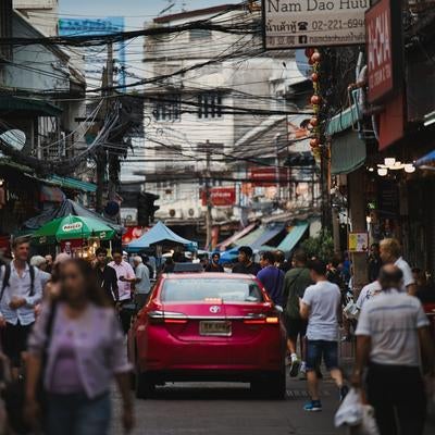 タクシーが走る東南アジアの雑踏路地の写真