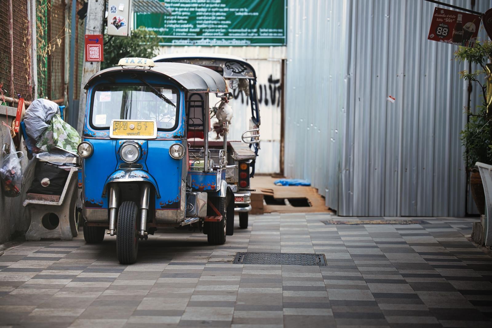 青いトゥクトゥクが石畳の路地裏に停車している様子