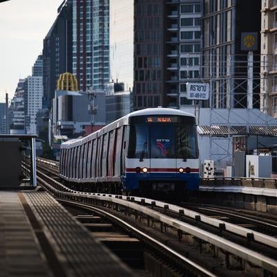 バンコクの高層ビル群を背景に走行するBTSスカイトレイン車両の写真
